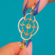 Gold floral Peridot pendant, front against blue background